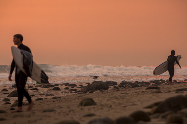 Surfers in Carpinteria paddle out to smoke-filled skies